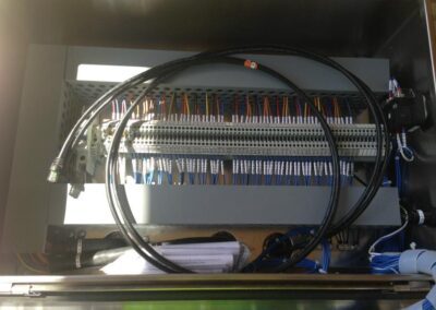 A wired electronic control panel with cables and connectors, enclosed in a metal casing.