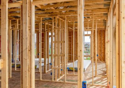 Wooden frames and beams in a partially constructed building, with drywall sheets on the floor.